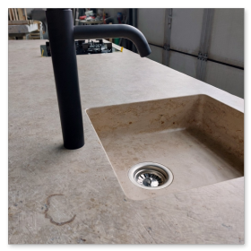 Massives Gartenwaschbecken aus beigem Jura Marmor mit fossilen Einschlüssen, eingebaut in eine Outdoor-Küche.