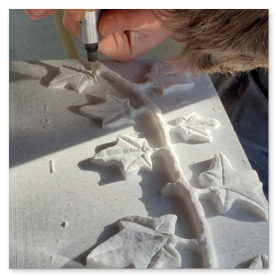 Nahaufnahme eines fein ziselierten Ornaments in hellem Marmor.