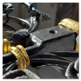 Nahaufnahme: Ein Steinmetz beim Auftragen von Blattgold auf Metallverzierungen.