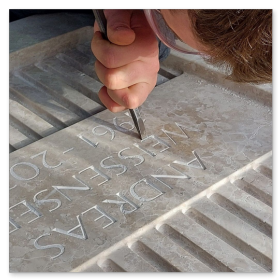 Steinmetzmeister bei der Bearbeitung eines Grabstein in der Marmorwerkstraße 50.